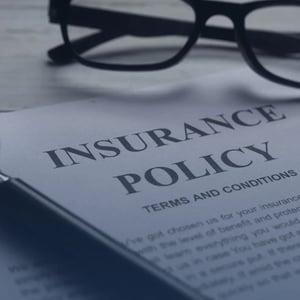 Glasses laying on a document that says insurance policy